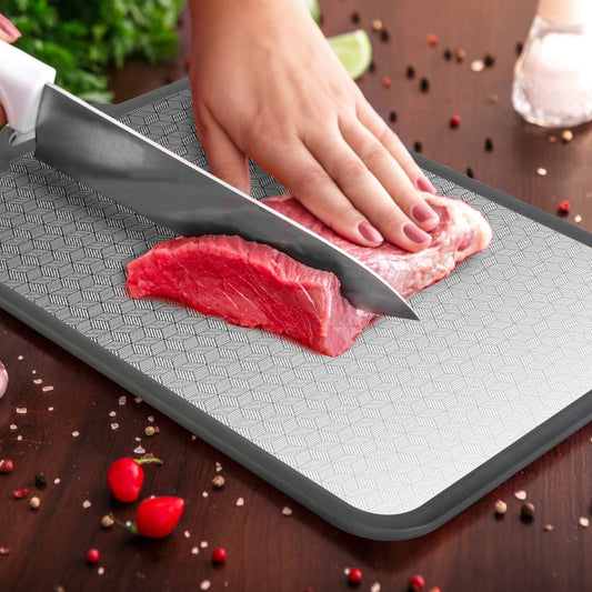 Close-up of raw meat being cut on textured cutting board surface