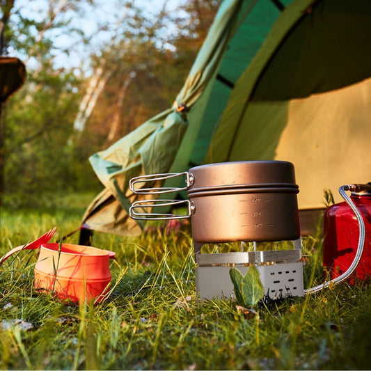 Backpacking stove heating a metal pot outdoors near a pitched tent