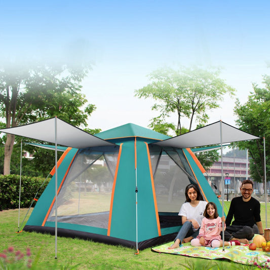 Large camping tent with side awnings set up in a park with people seated nearby