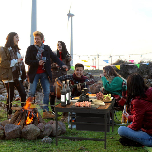 Camping table near a fire pit with food during an outdoor group gathering