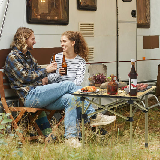 Camping table in use near an RV with people seated outdoors