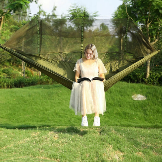 Person sitting on a suspended hammock with mosquito net in open outdoor area