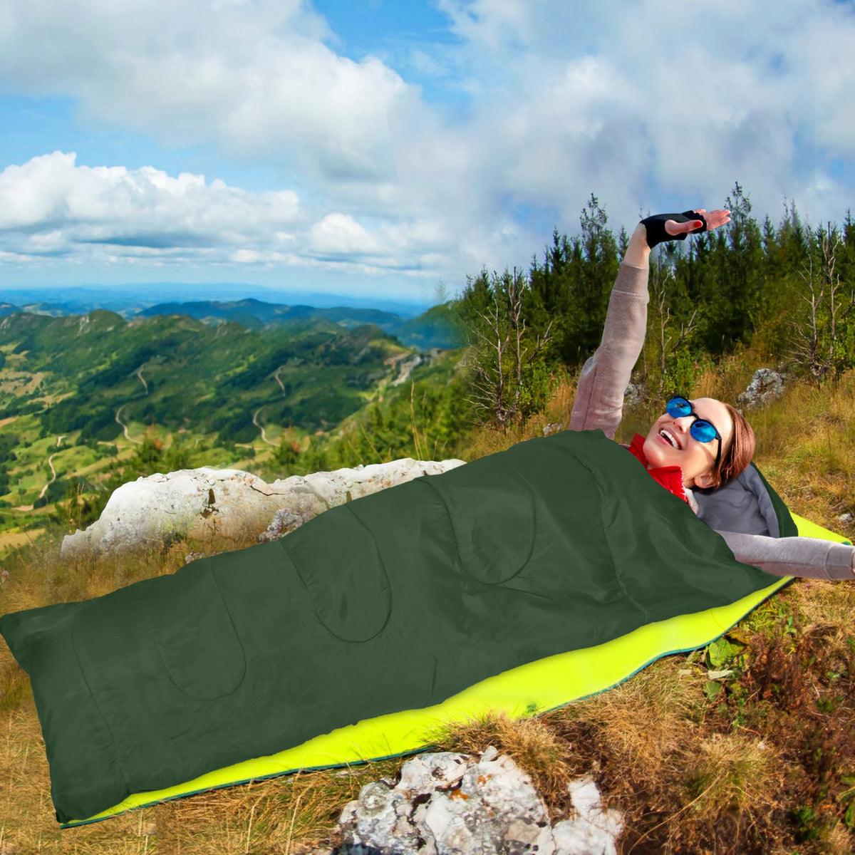 Person lying on a green sleeping bag with a scenic mountain view in the background