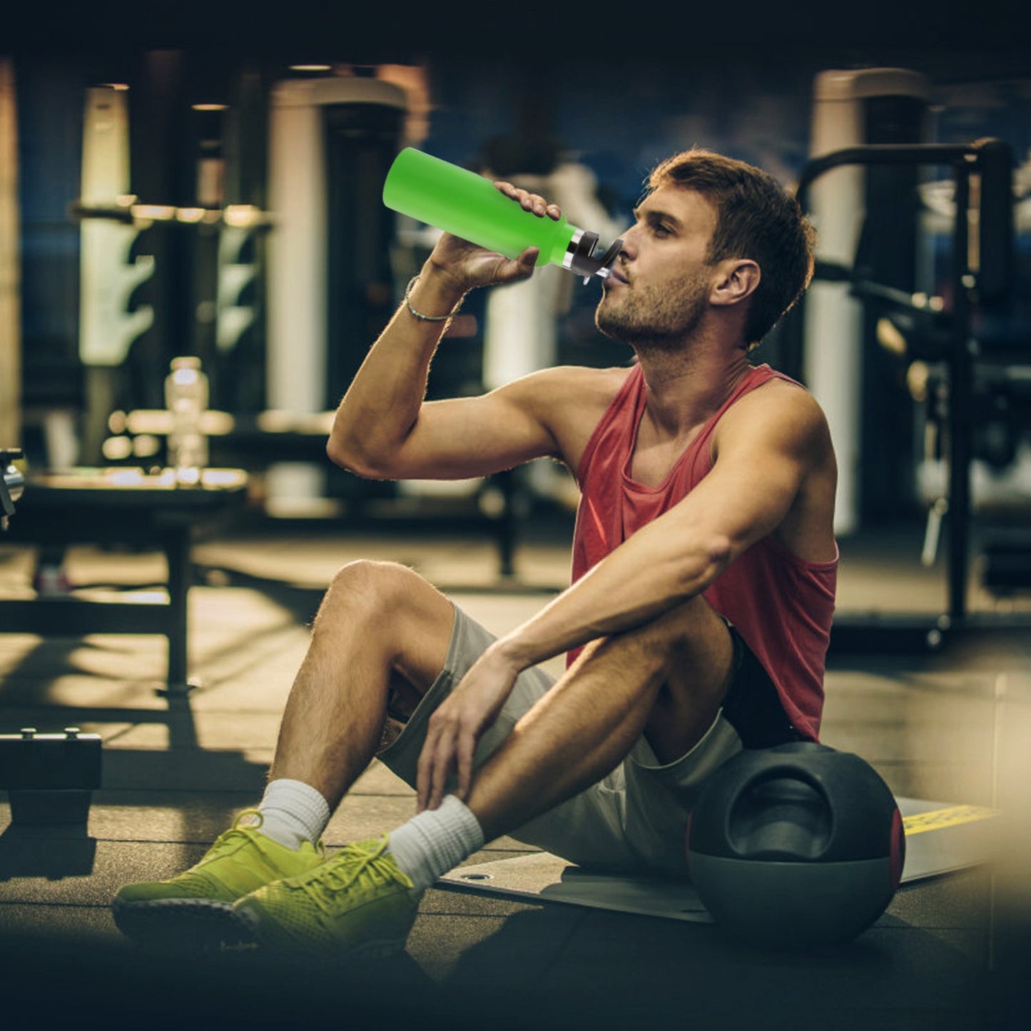 Man drinking from a green protein shake bottle in a gym setting