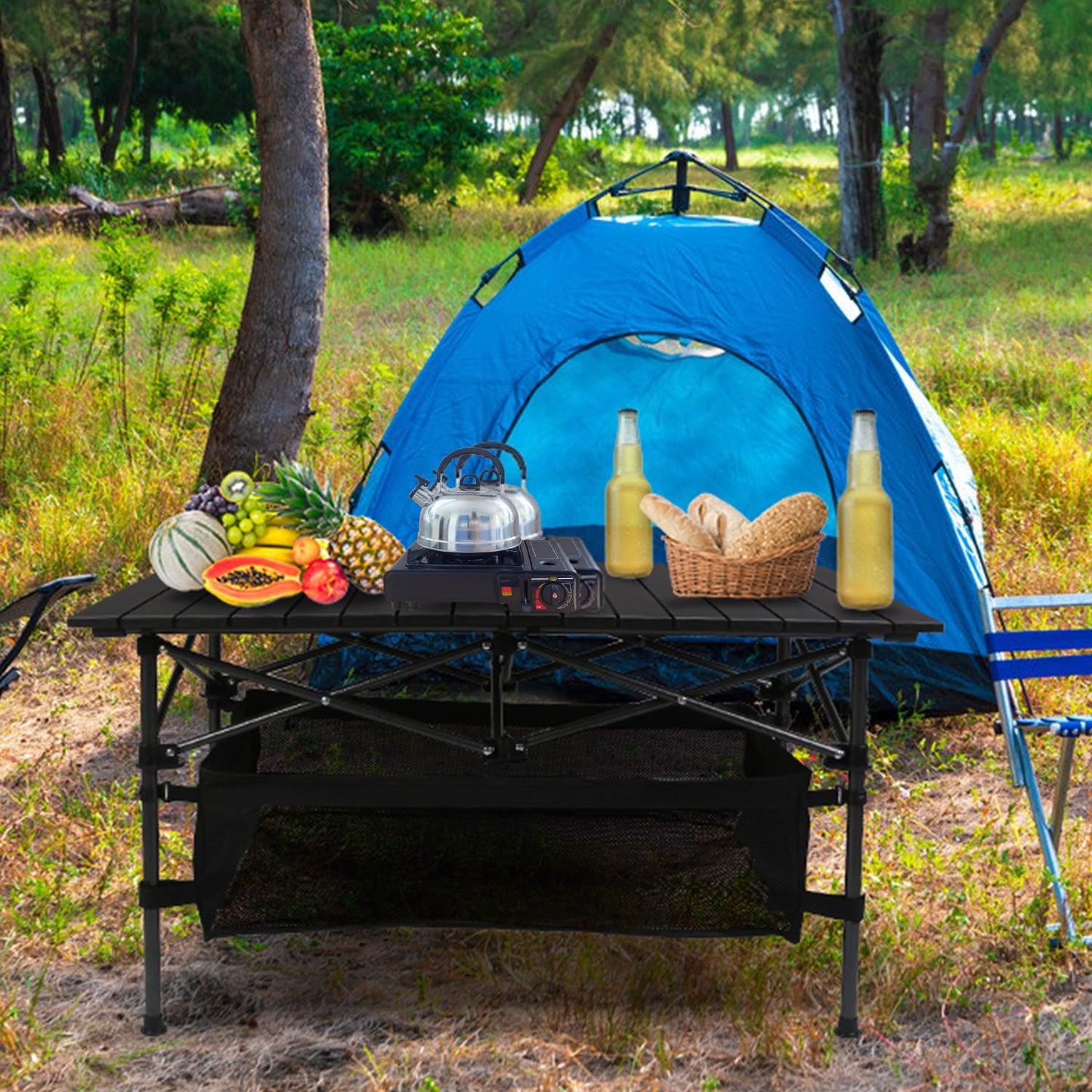 Camping setup with a blue tent, table, stove, and food items in a natural setting.