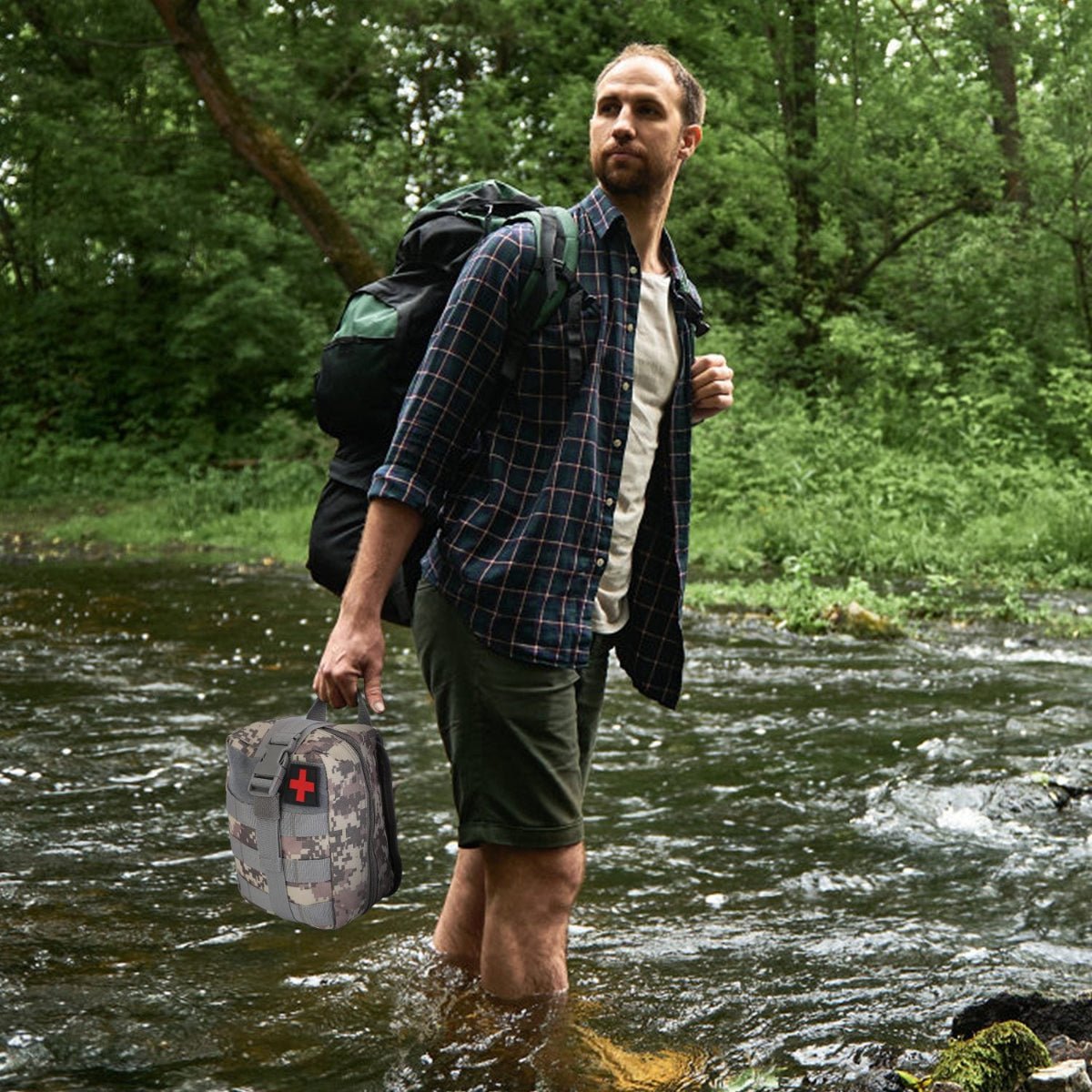 Hiker wading through a stream carrying a camouflage first aid pouch