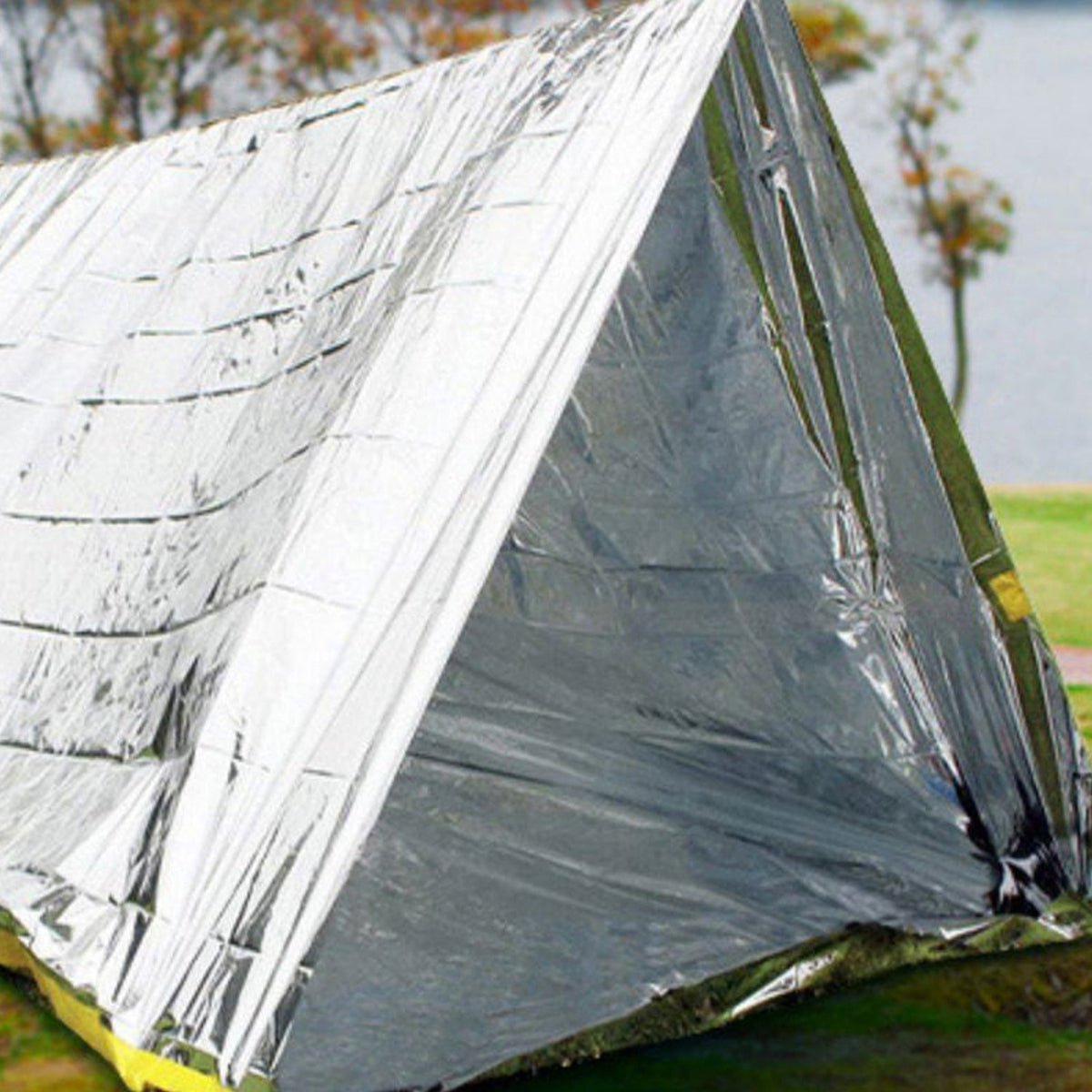 Emergency reflective shelter set up outdoors on grassy ground