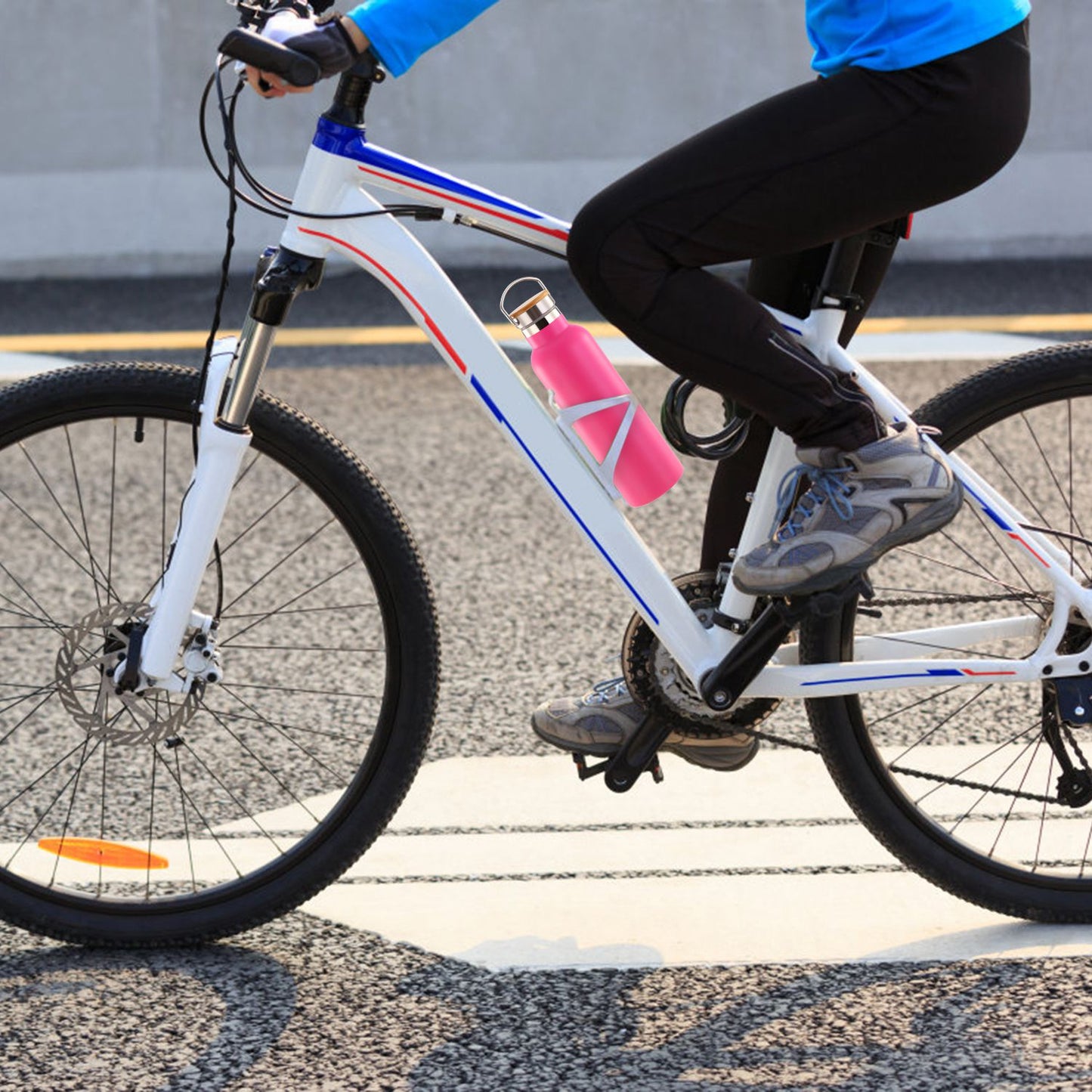 Person riding a bicycle with a pink water bottle attached, on a road.