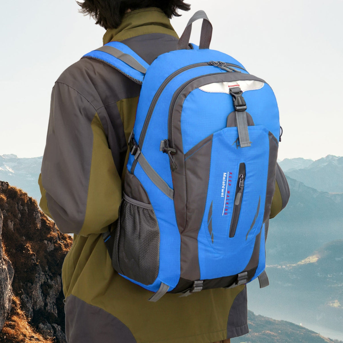 Person wearing a blue and gray backpack with a mountainous landscape in the background