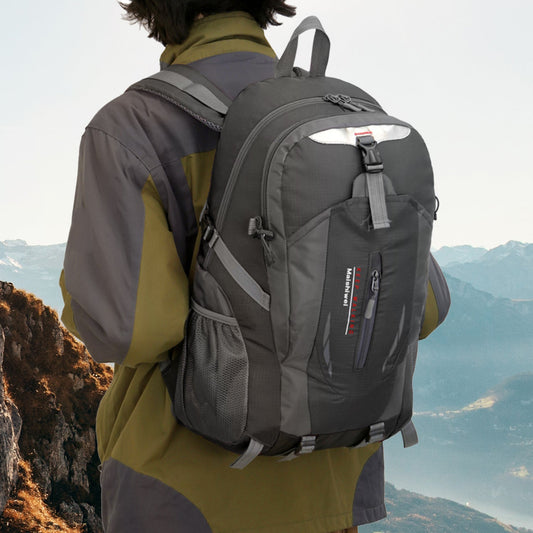 Person wearing a gray backpack with a mountainous landscape in the background