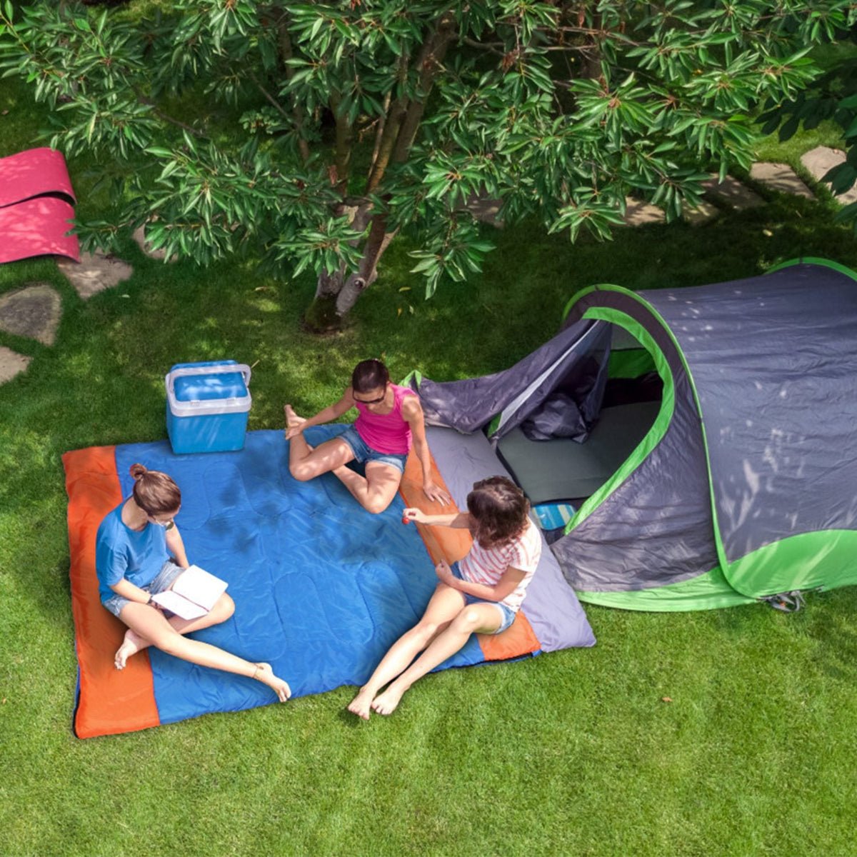 Double sleeping bag laid out outdoors at a campsite with two people inside