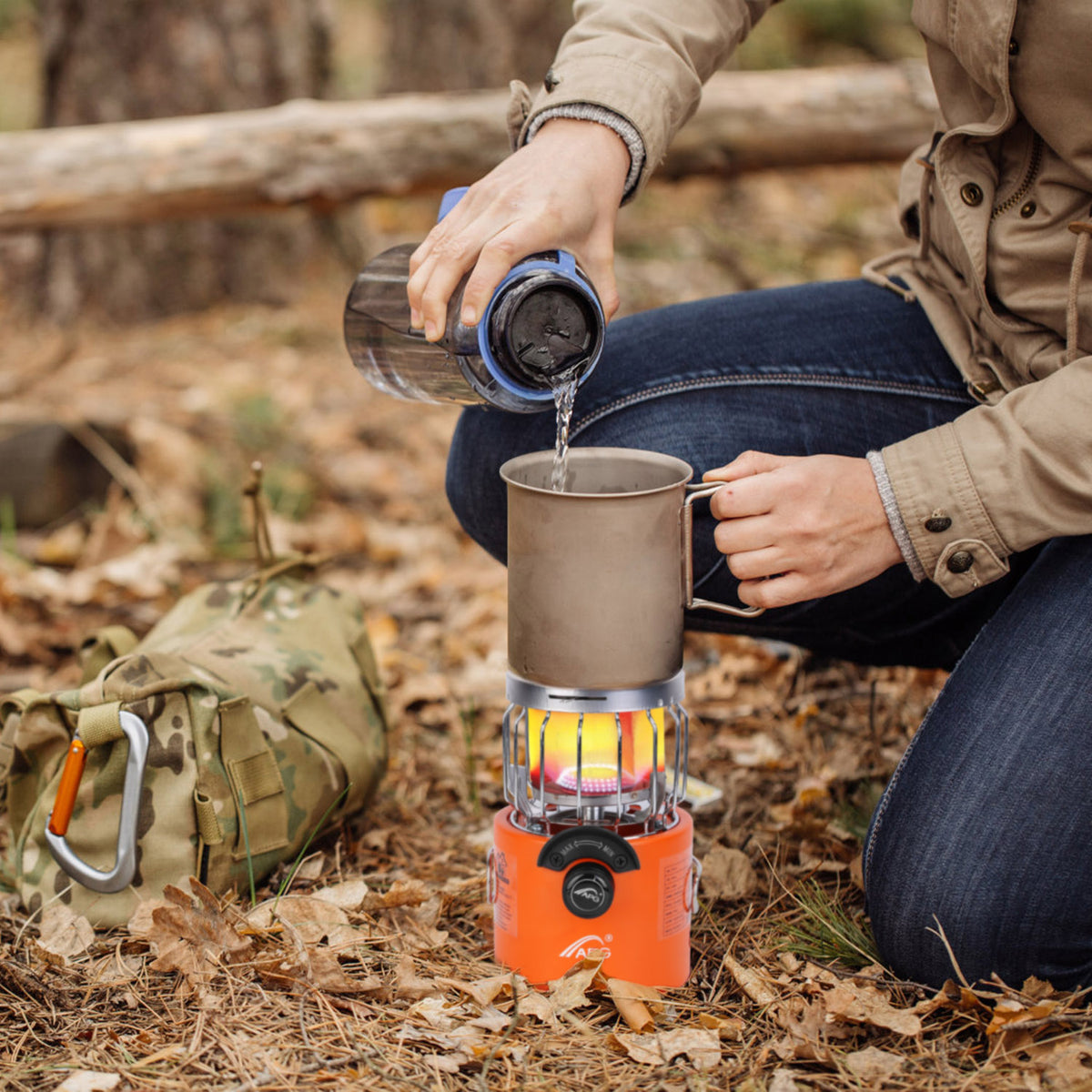 Person outdoors using a camping stove to heat water in a mug.