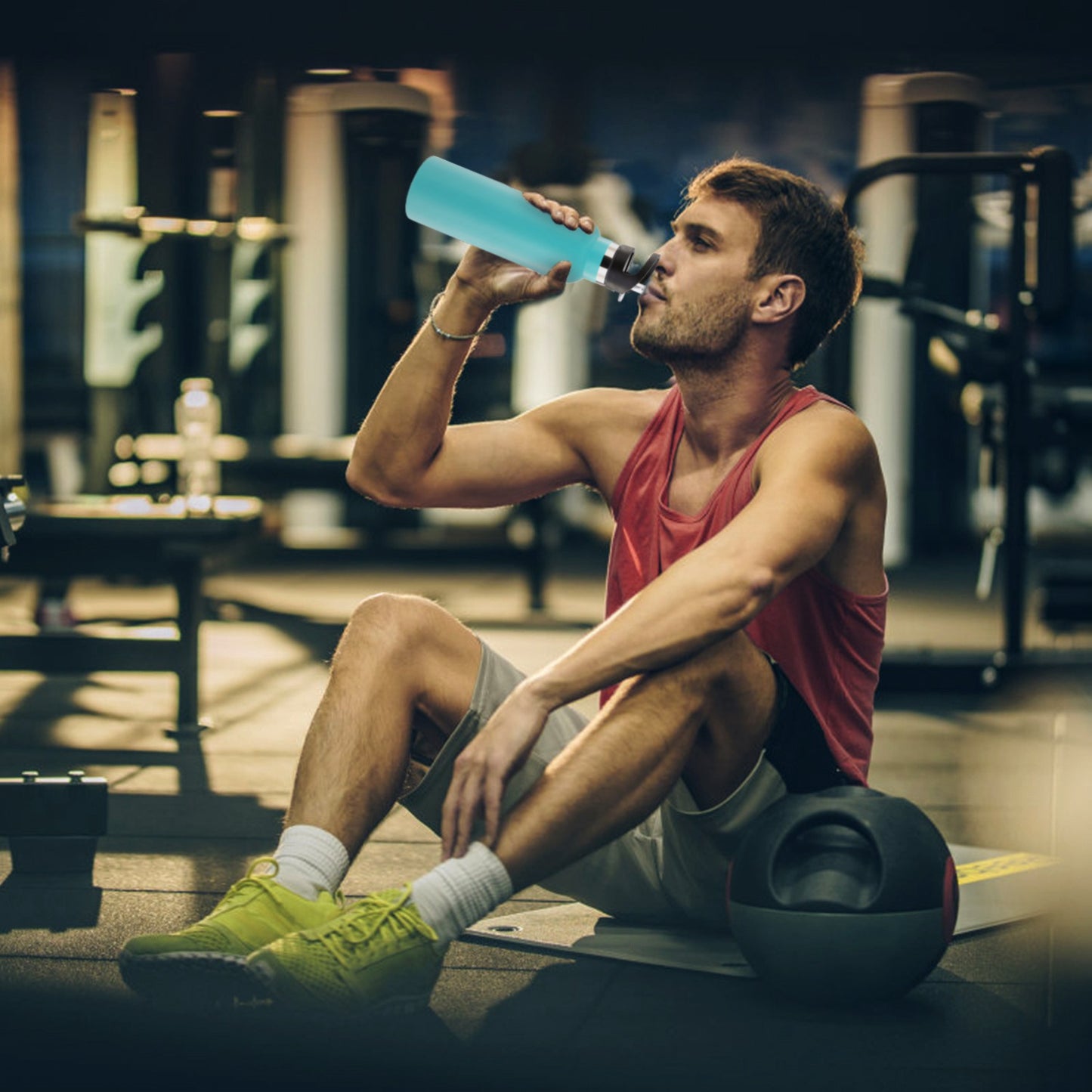 Man drinking from a blue water bottle in a gym setting