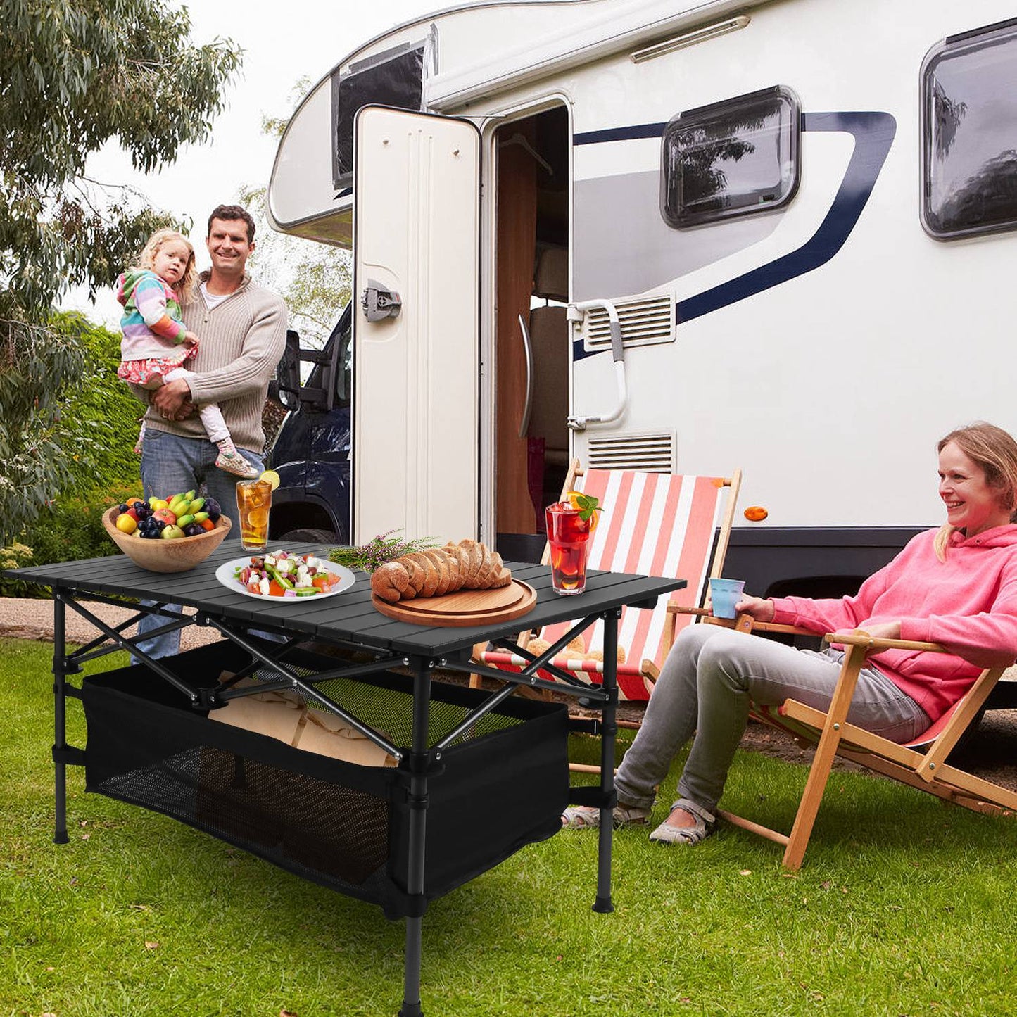 Family enjoying a picnic in front of an RV with a table set up.