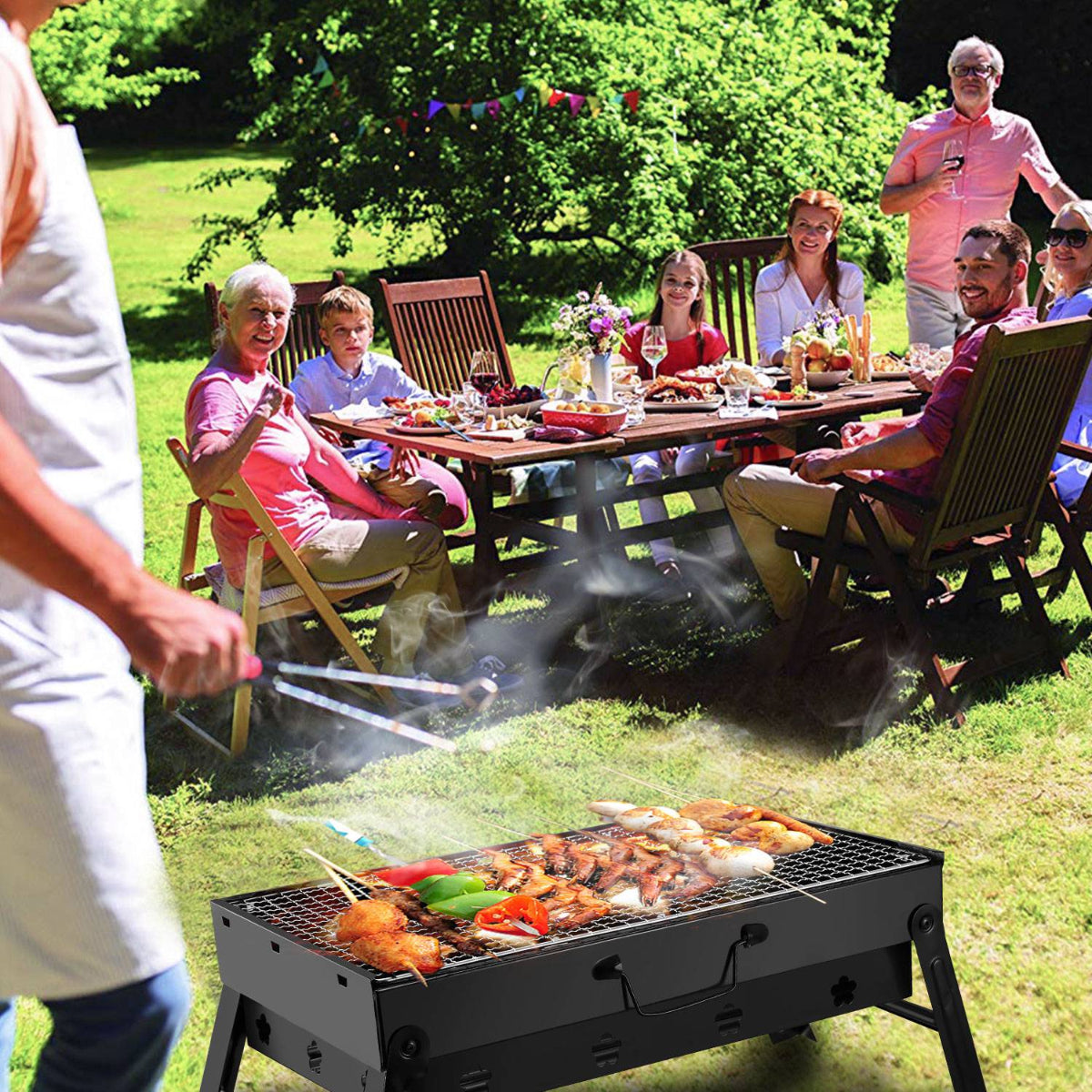 People enjoying a barbecue outdoors with food on a grill and a table with drinks and plates.