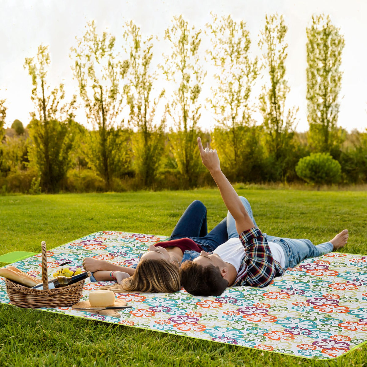 Two people lying on a colorful picnic blanket in a park