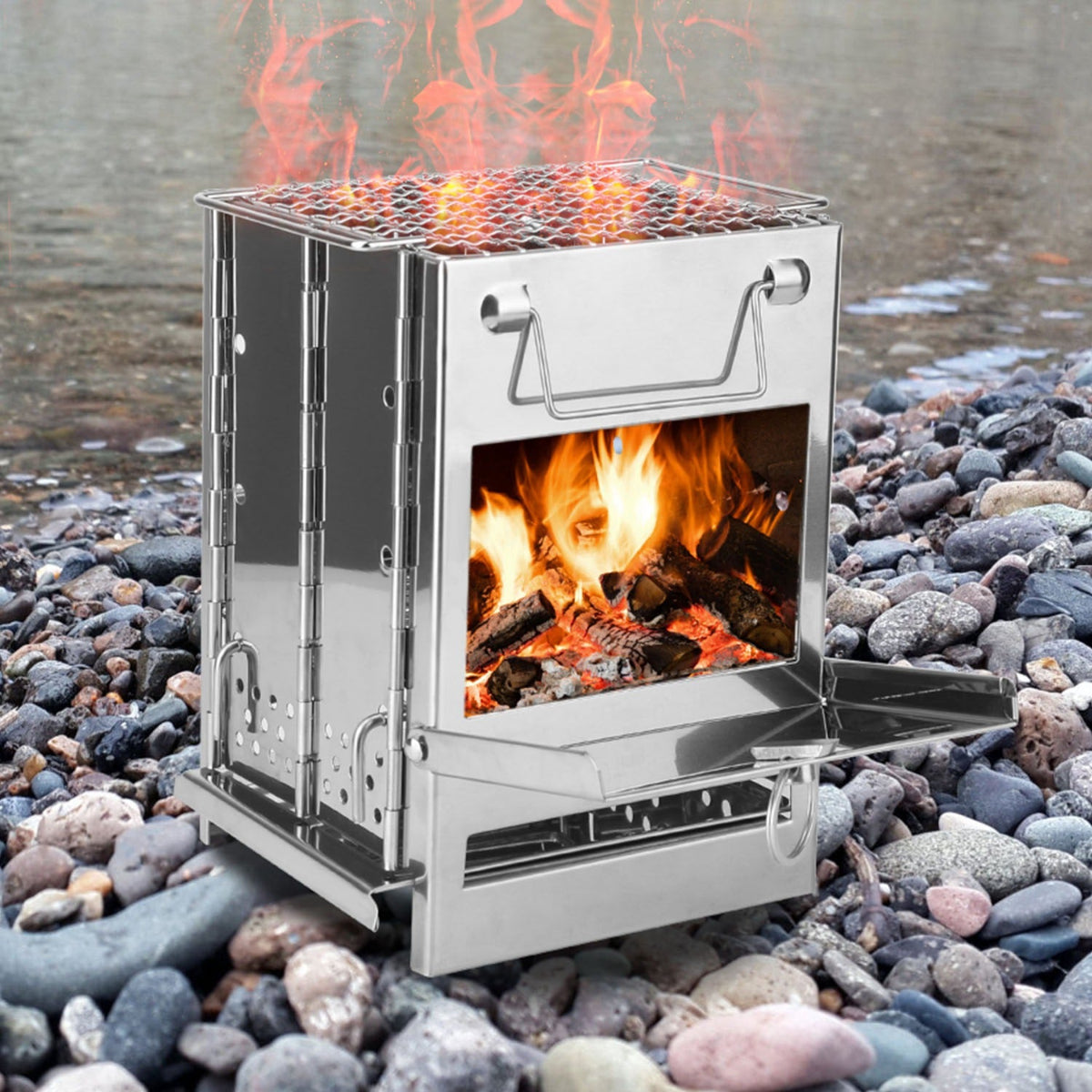 Portable metal stove with fire burning on a rocky surface near water