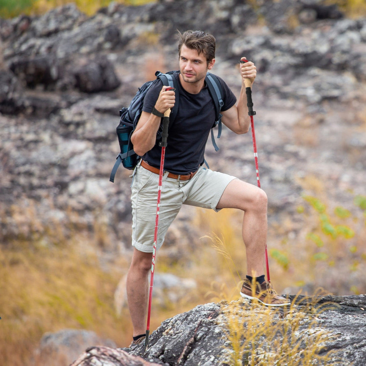 Man hiking on a rocky trail with backpack and red walking sticks