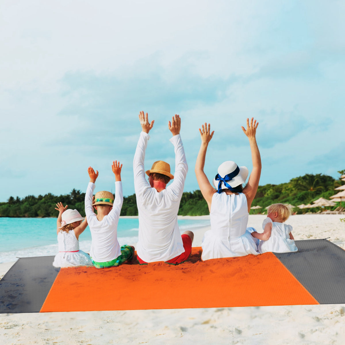 Family with children practicing yoga on a beach with a clear blue sky.