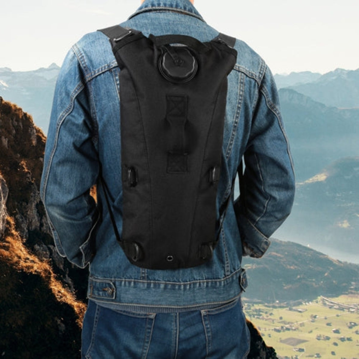 Person wearing a black backpack with a scenic mountain view in the background