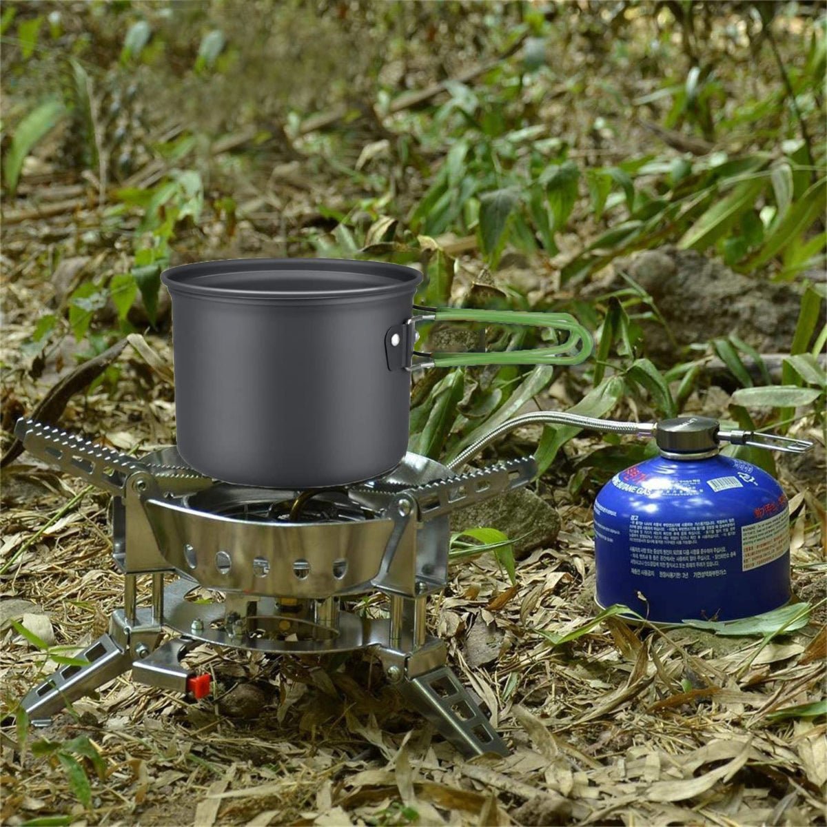Single aluminum pot heating on compact gas stove beside fuel canister outdoors