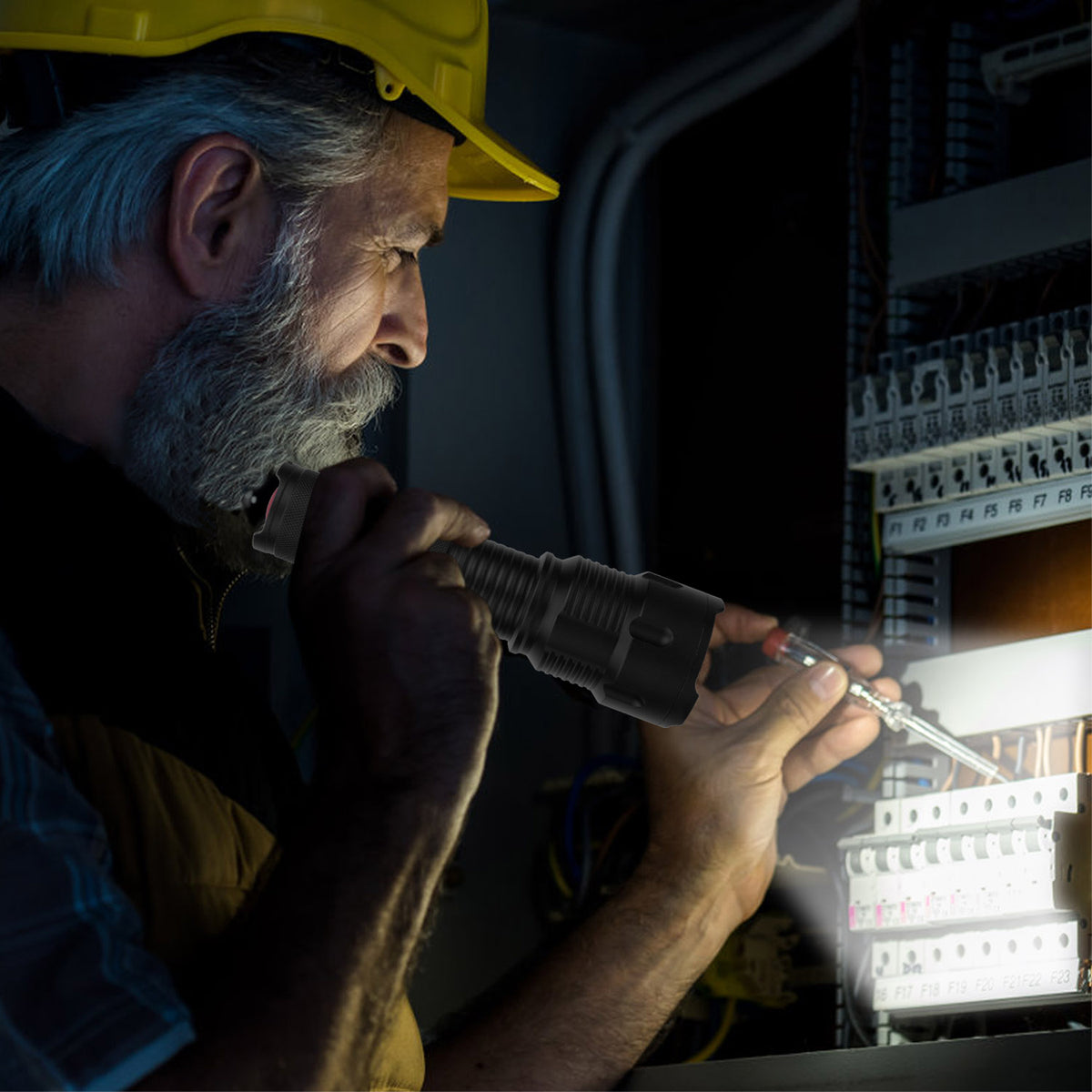 Man in a hard hat using a flashlight to inspect electrical panels.