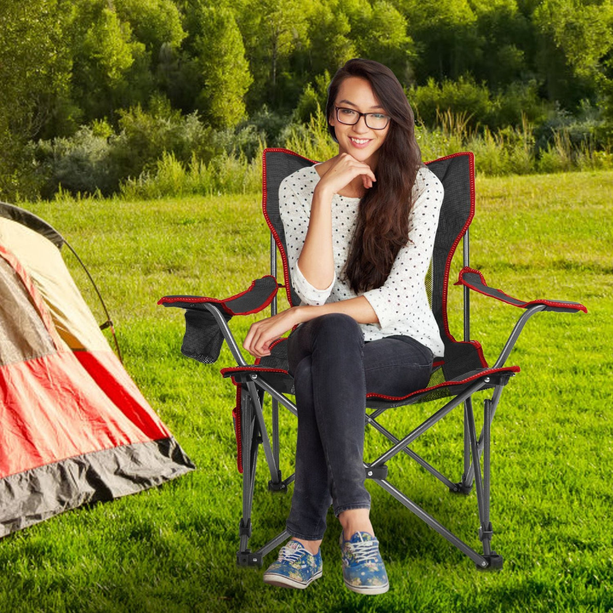 Woman sitting on a camping chair in a grassy field with a tent in the background