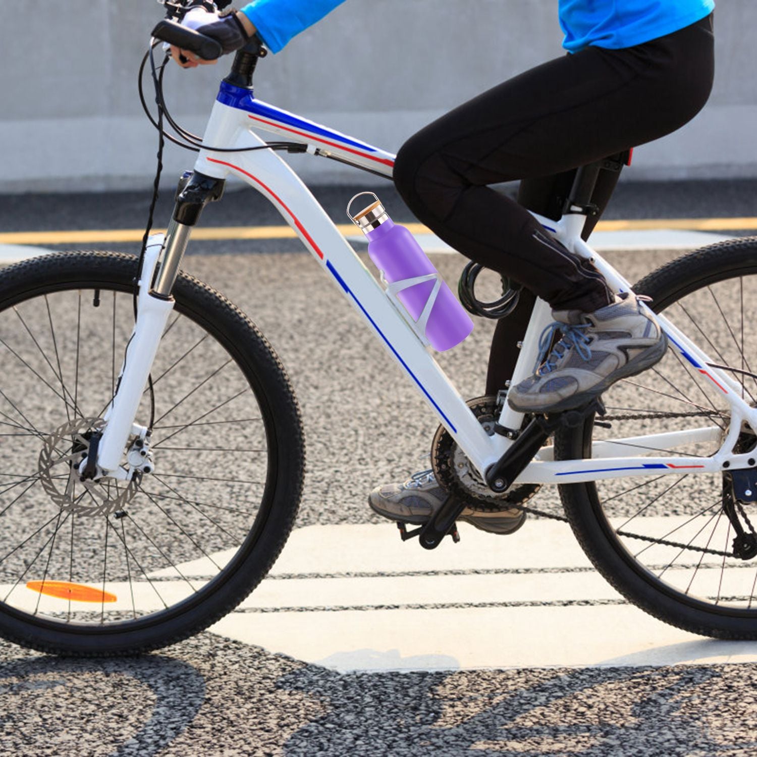 Person riding a bicycle with a purple water bottle attached on a road.