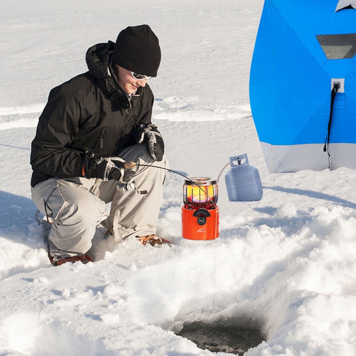 Camping stove heater in use on snow near an ice fishing shelter