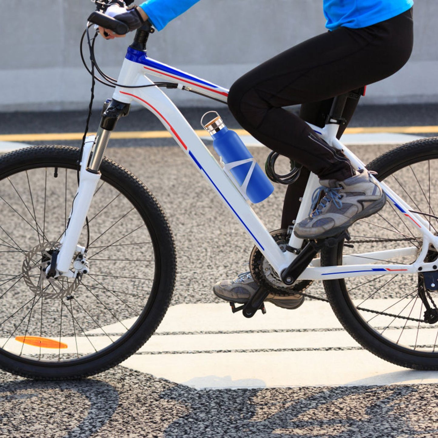Person riding a bicycle with a blue water bottle attached, on a road.