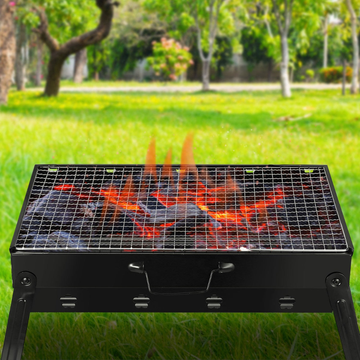 Portable grill with flames on a grassy outdoor background