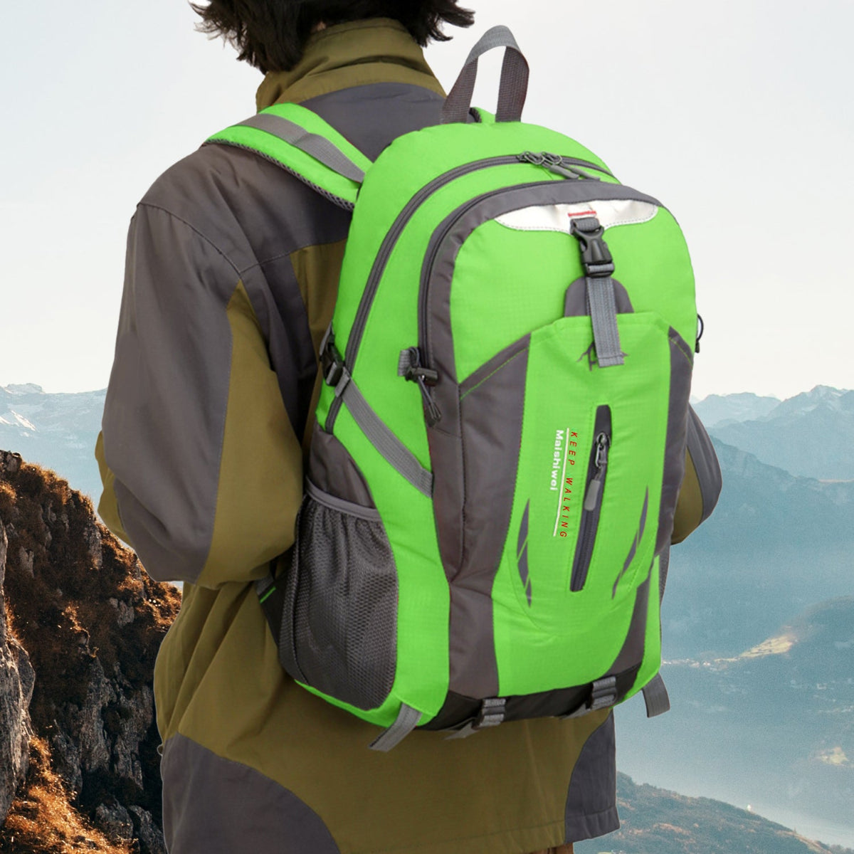 Person wearing a green and gray backpack with a mountainous landscape in the background