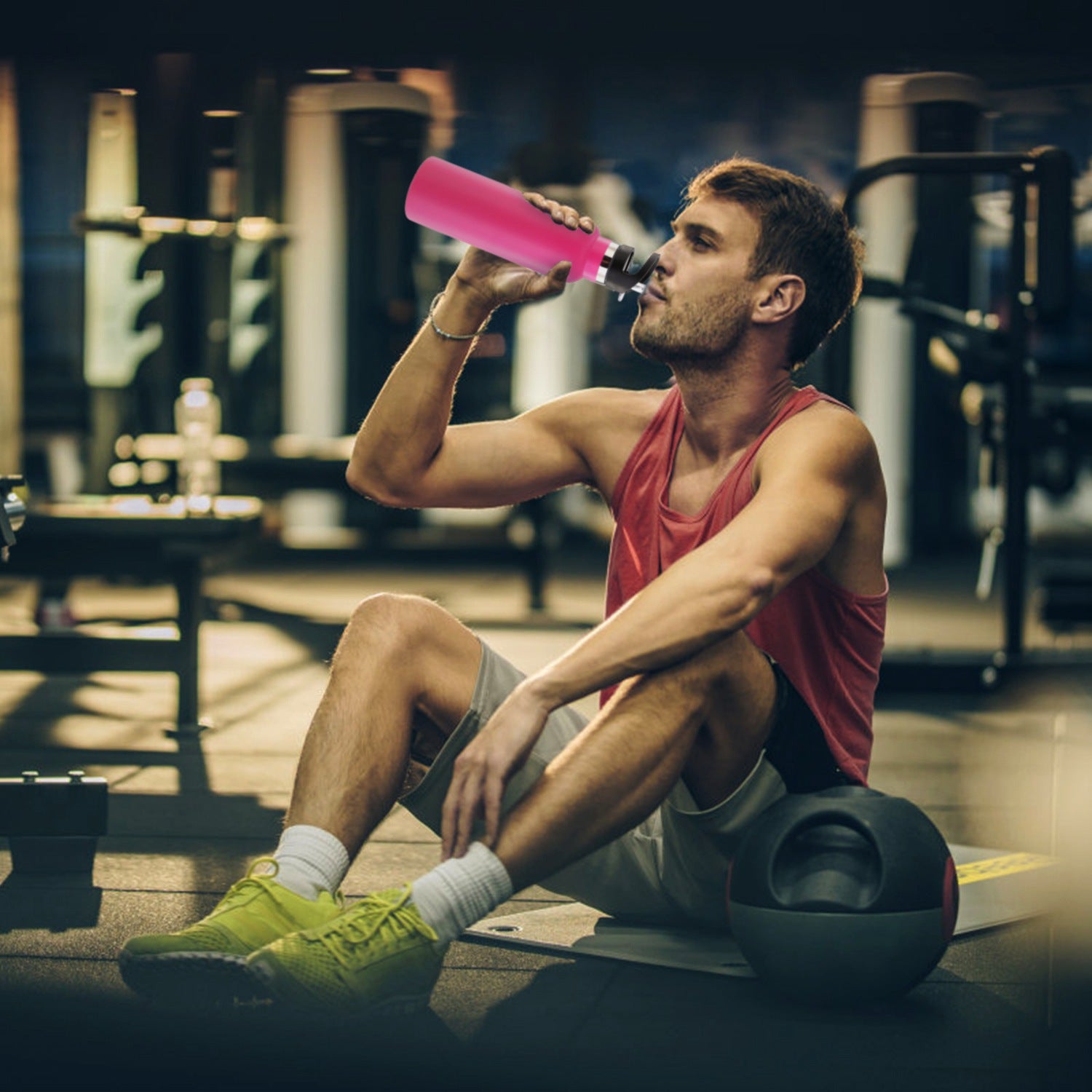 Man in a gym drinking from a pink bottle