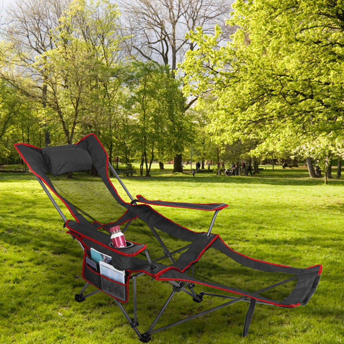 Foldable camping chair with cup holder on grass in a park