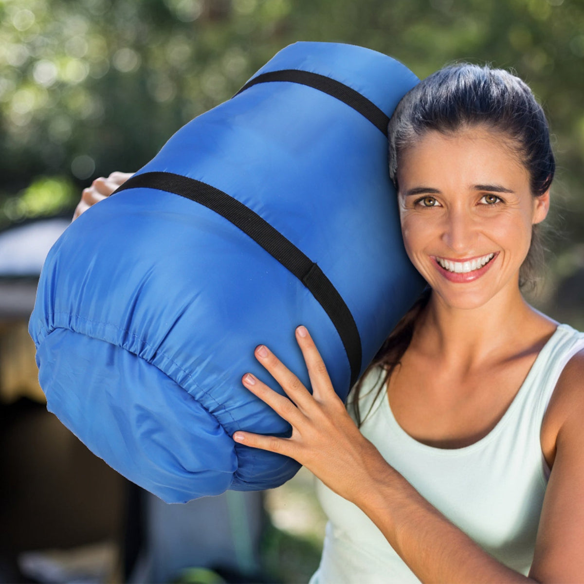 Woman holding a blue sleeping bag outdoors
