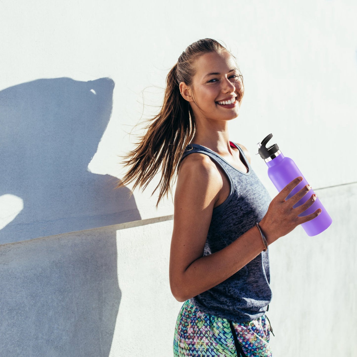 Woman holding a purple water bottle against a light background