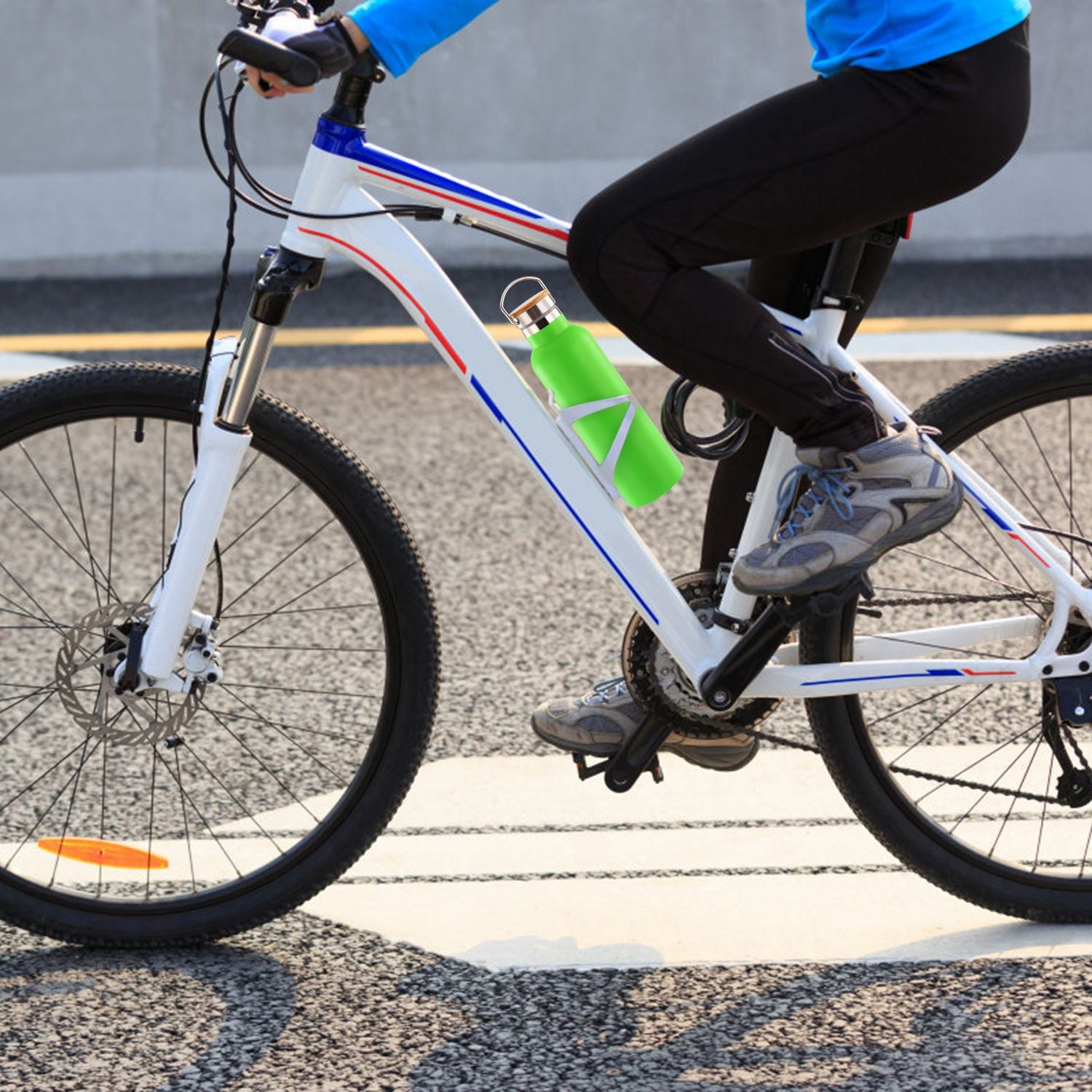 Person riding a bicycle with a green water bottle attached on a road.