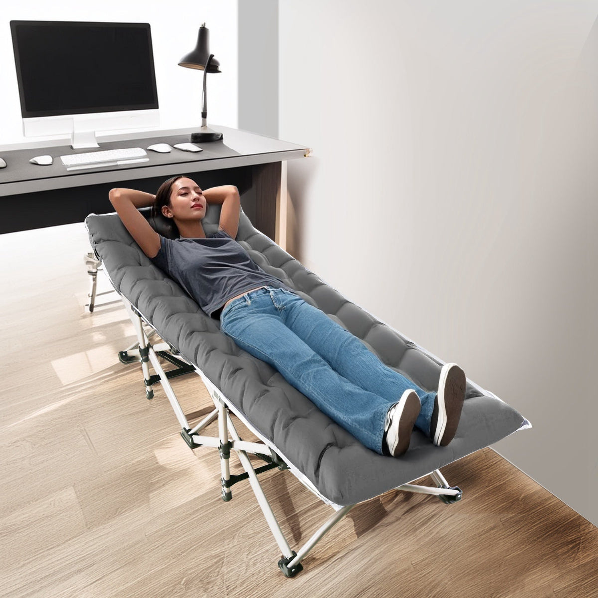 Person lying on a gray folding bed in a home office setting