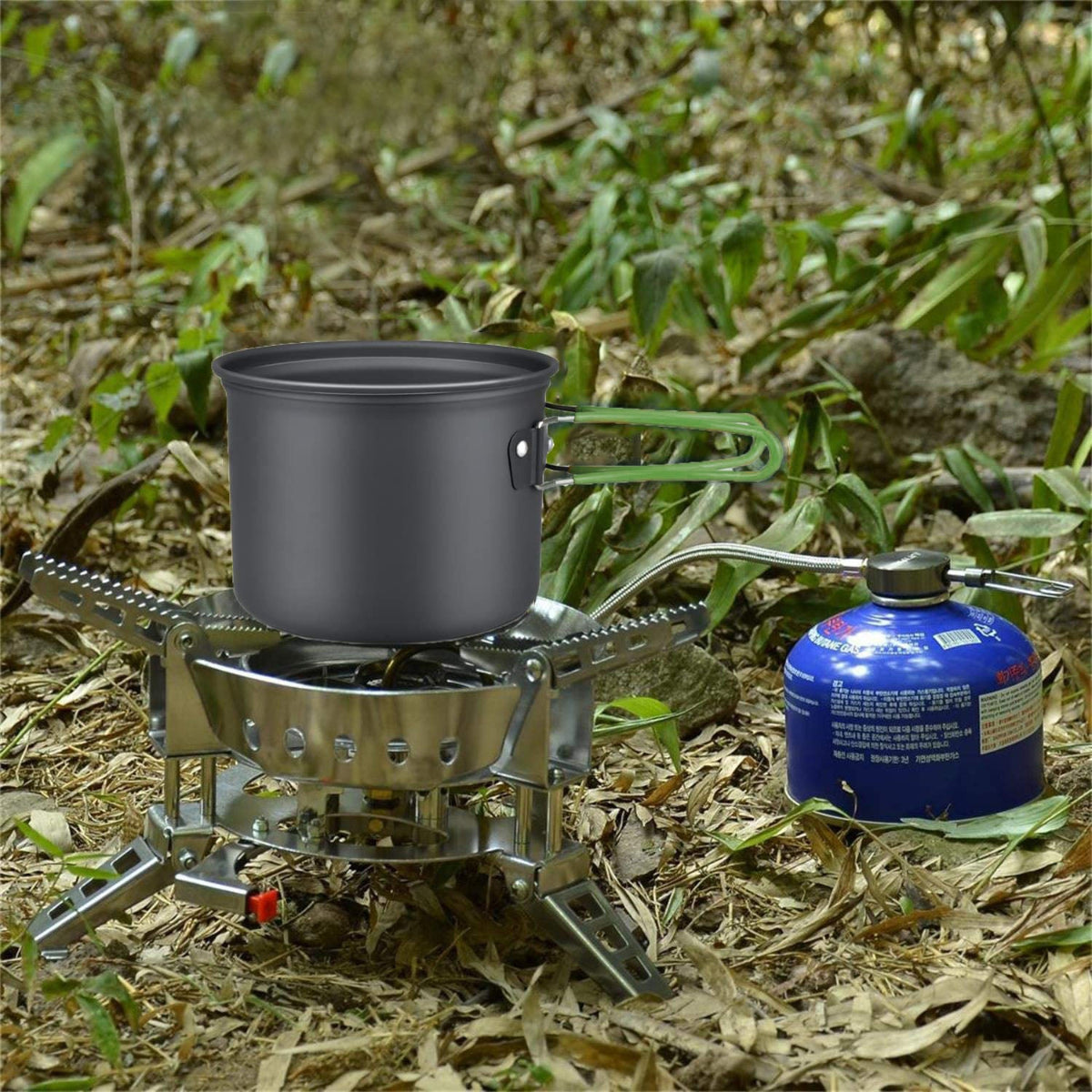 Portable camping stove with pot and gas canister on a natural ground surface