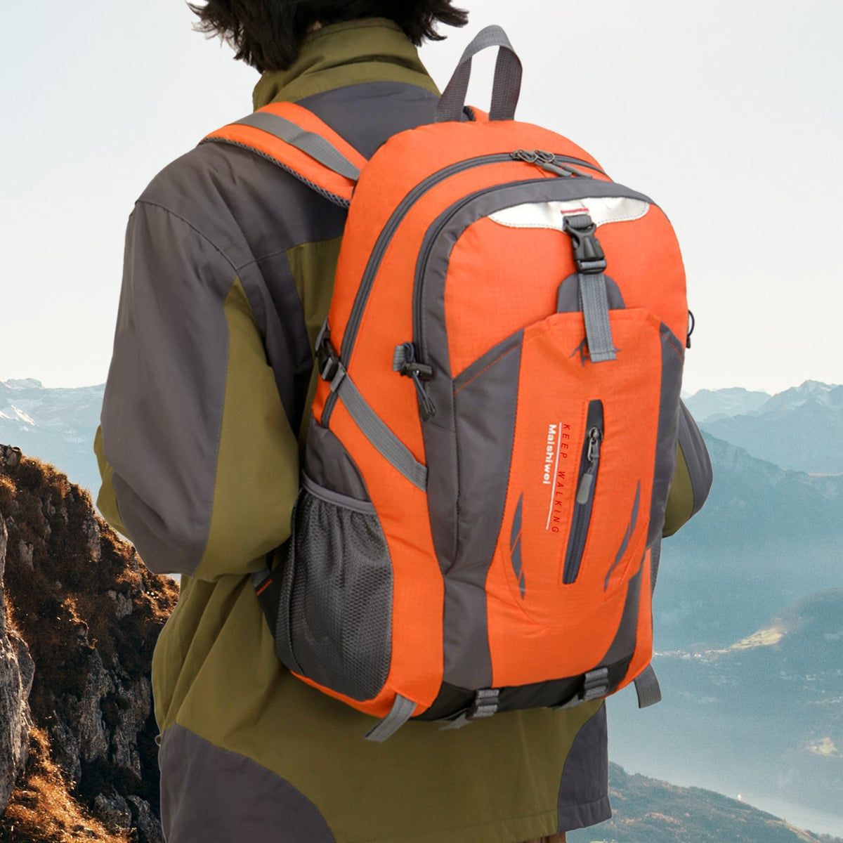 Person wearing an orange and gray backpack with a mountainous landscape in the background