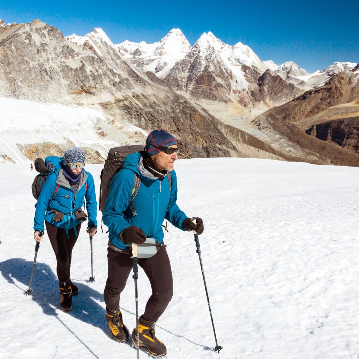 Hikers using folding aluminum trekking poles on a rocky mountain trail