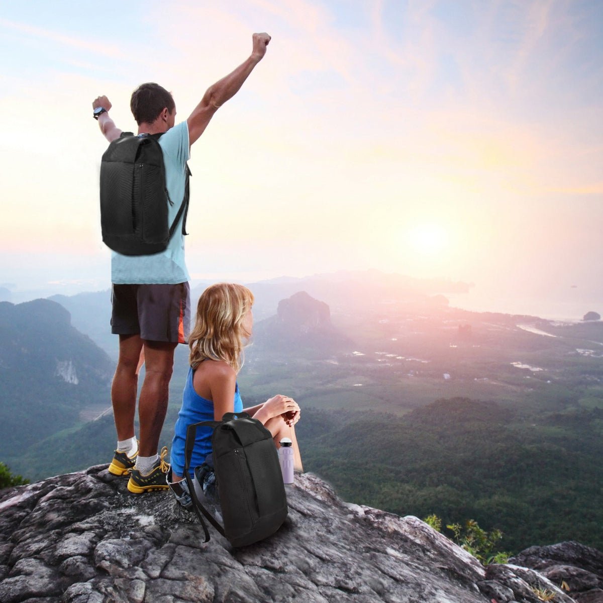 Two hikers on rocky overlook wearing compact backpacks above a valley landscape