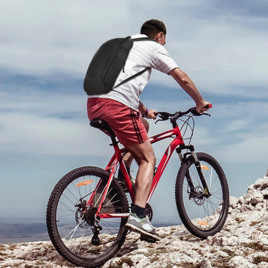 Person cycling uphill on rocky terrain wearing a slim black daypack