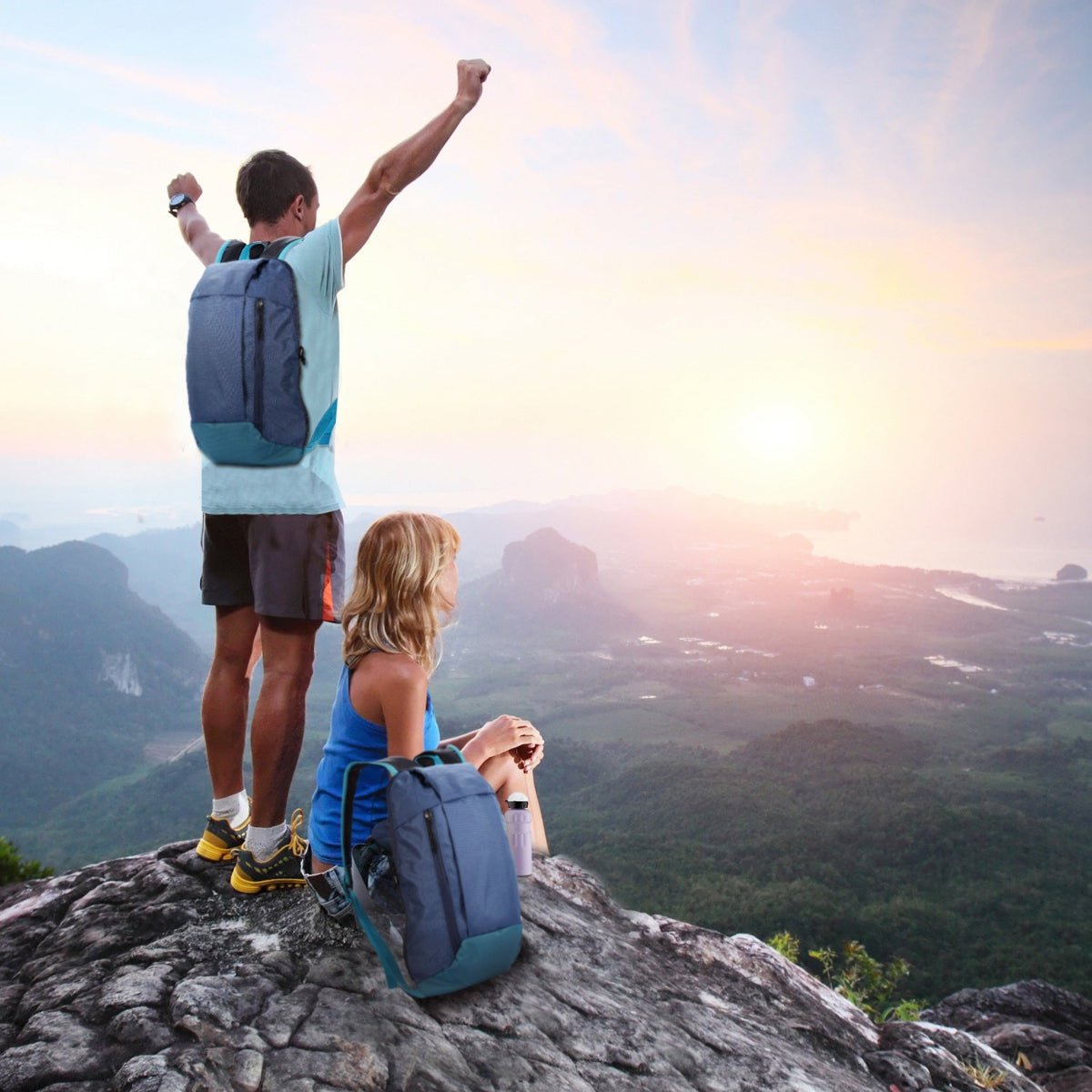 Hikers resting on a cliff edge with backpacks beside them at sunrise