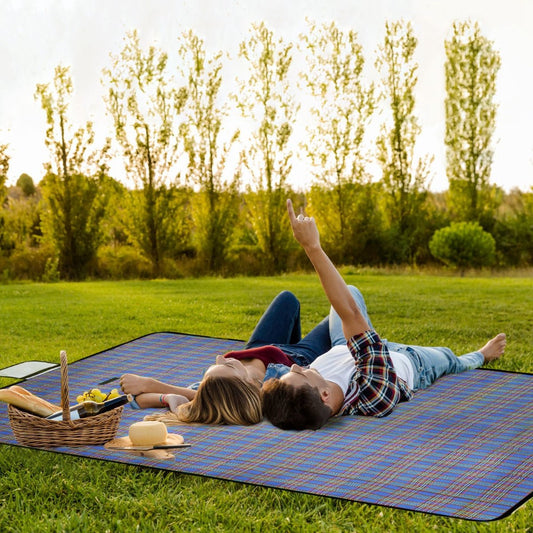 Plaid picnic blanket laid flat on grass with two people relaxing outdoors