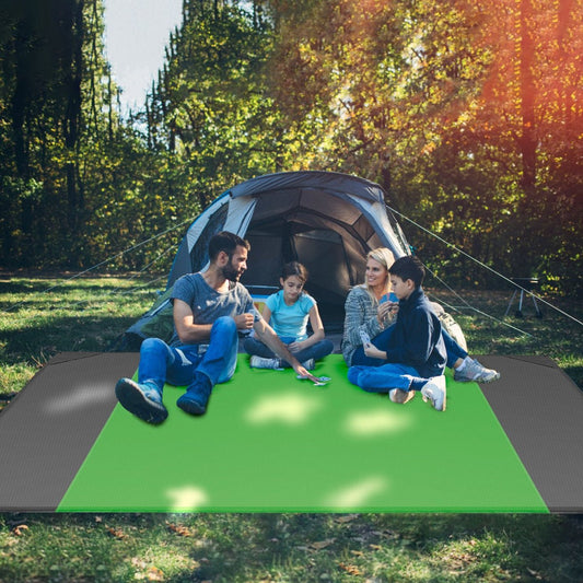 People seated on foldable outdoor mat at a campsite