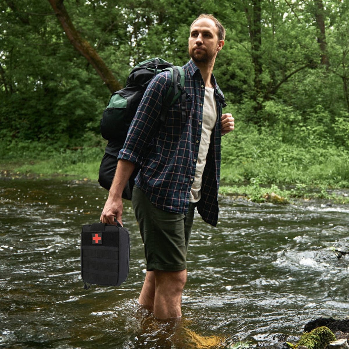 Hiker crossing a shallow stream holding a black first aid kit