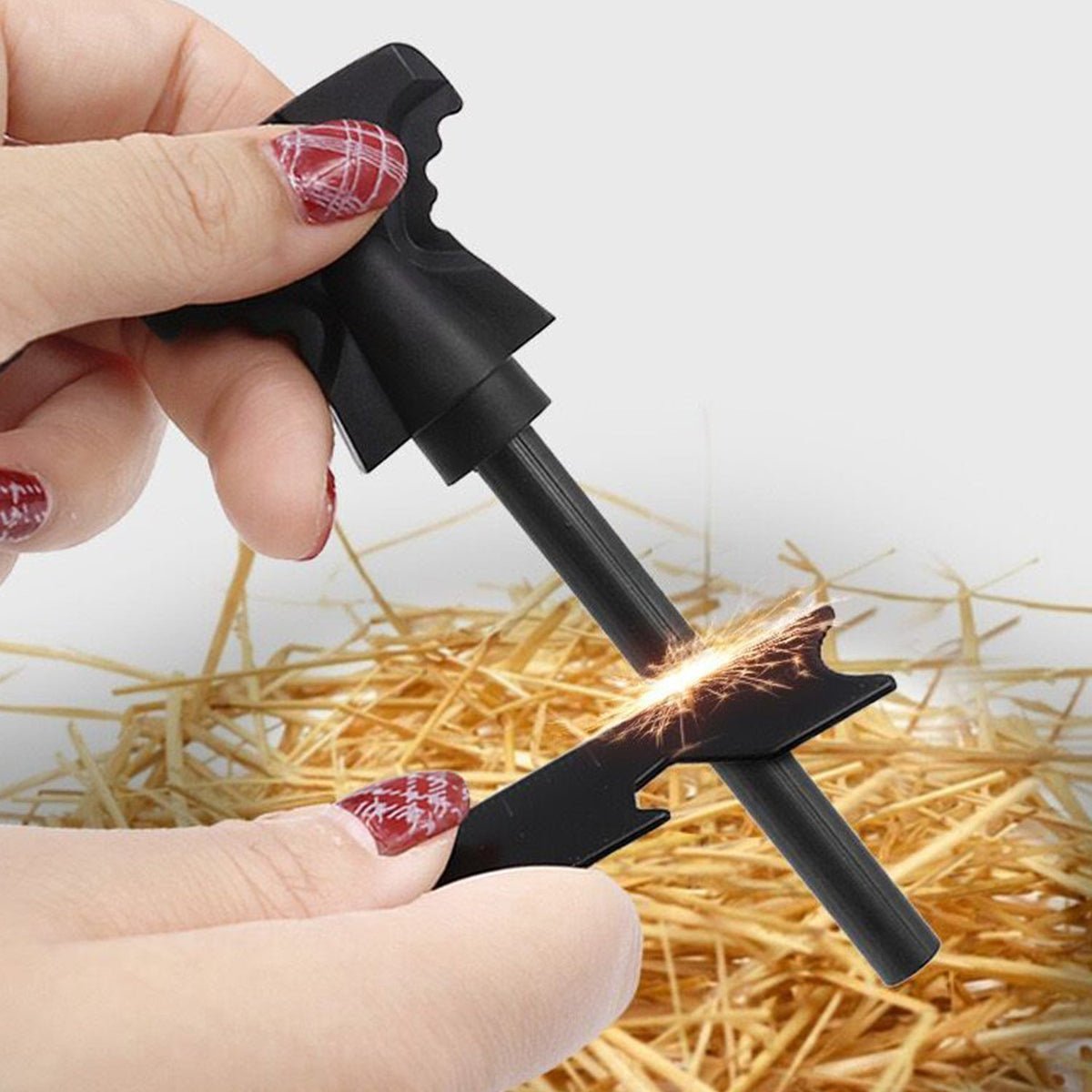 Hands using a fire starter to create sparks on dry straw