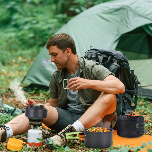 Camper cooking outdoors beside a tent using compact pots on a backpacking stove