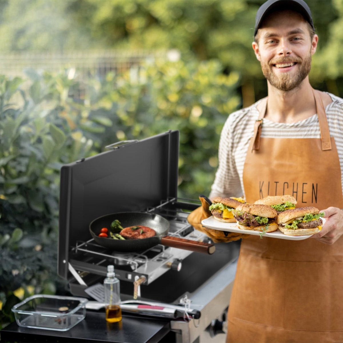 Three-burner camping stove set outdoors with food cooking beside a campsite table